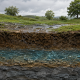Illustration photoréaliste en coupe du sol montrant l’infiltration de l’eau de pluie et la formation d’une nappe phréatique